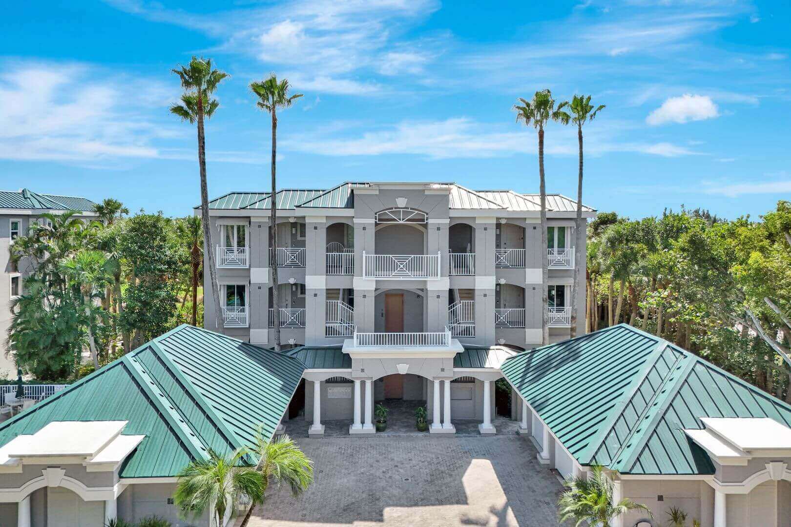 Elegant building with palm trees and blue sky.