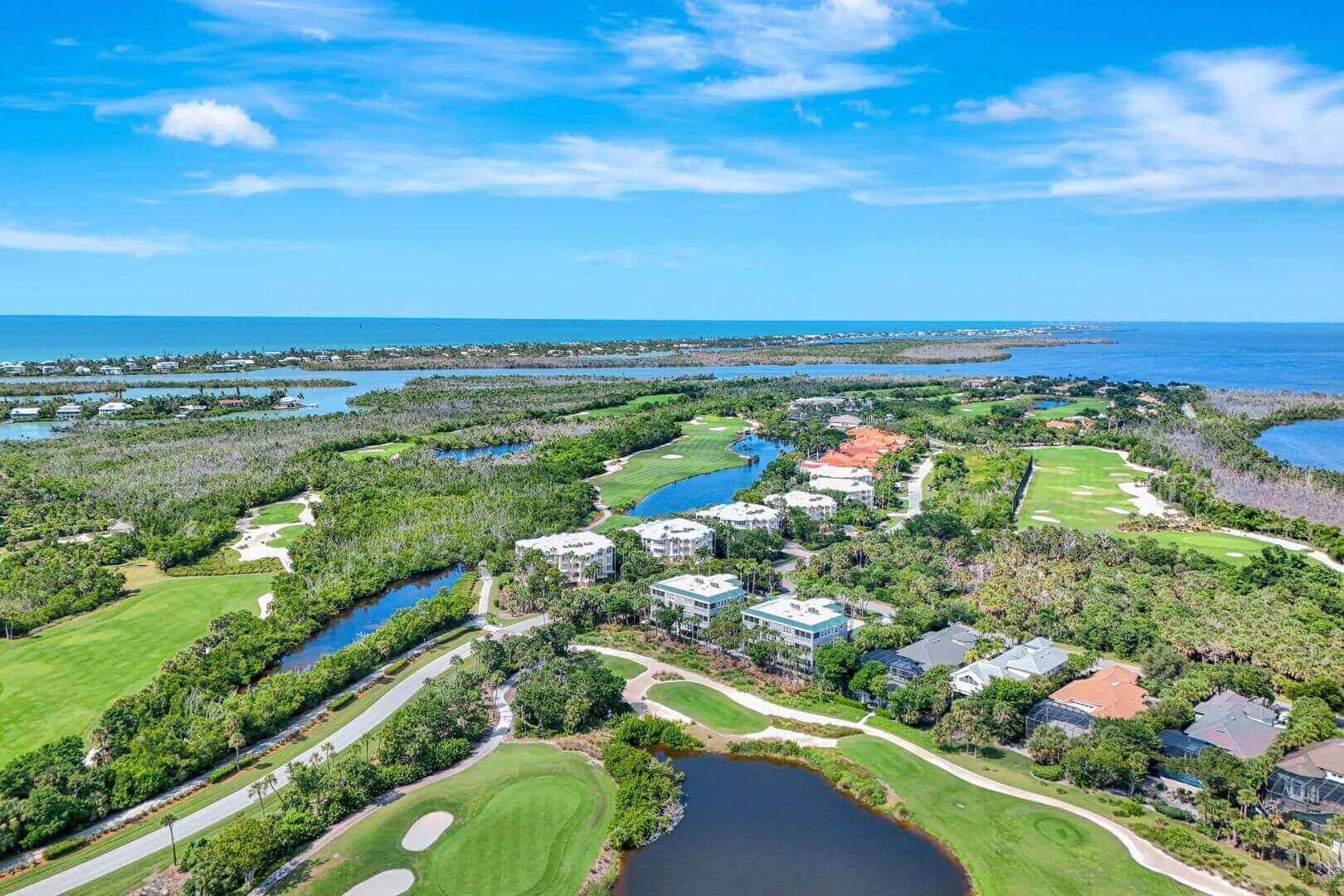 Coastal golf course with surrounding greenery and water.