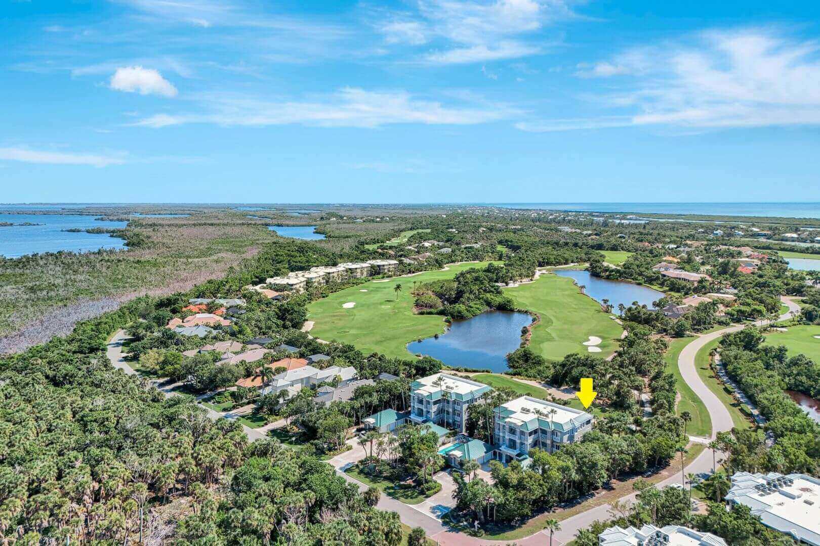 Golf course with surrounding greenery and buildings.