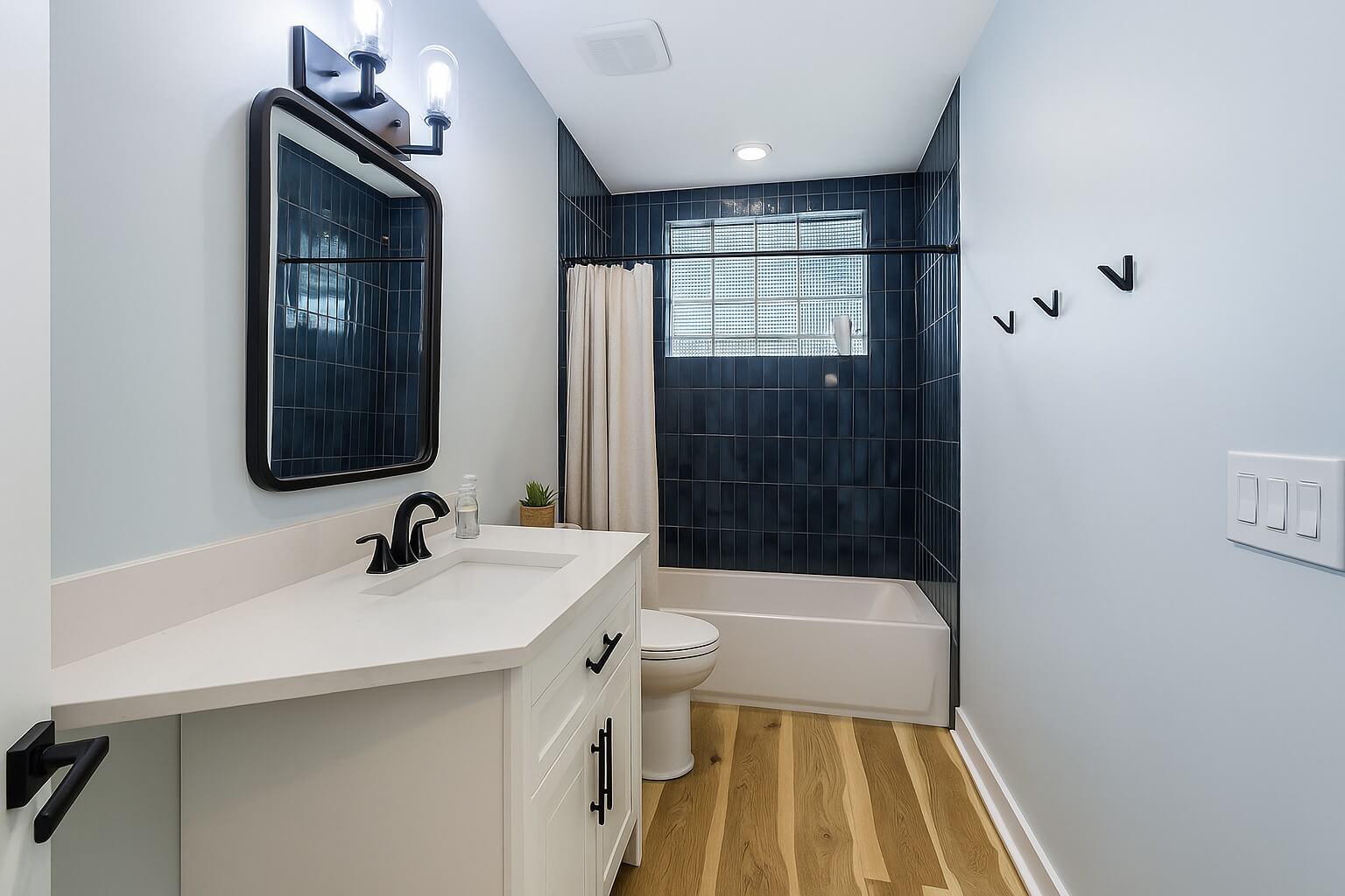 Modern bathroom with black tile and wood floor.