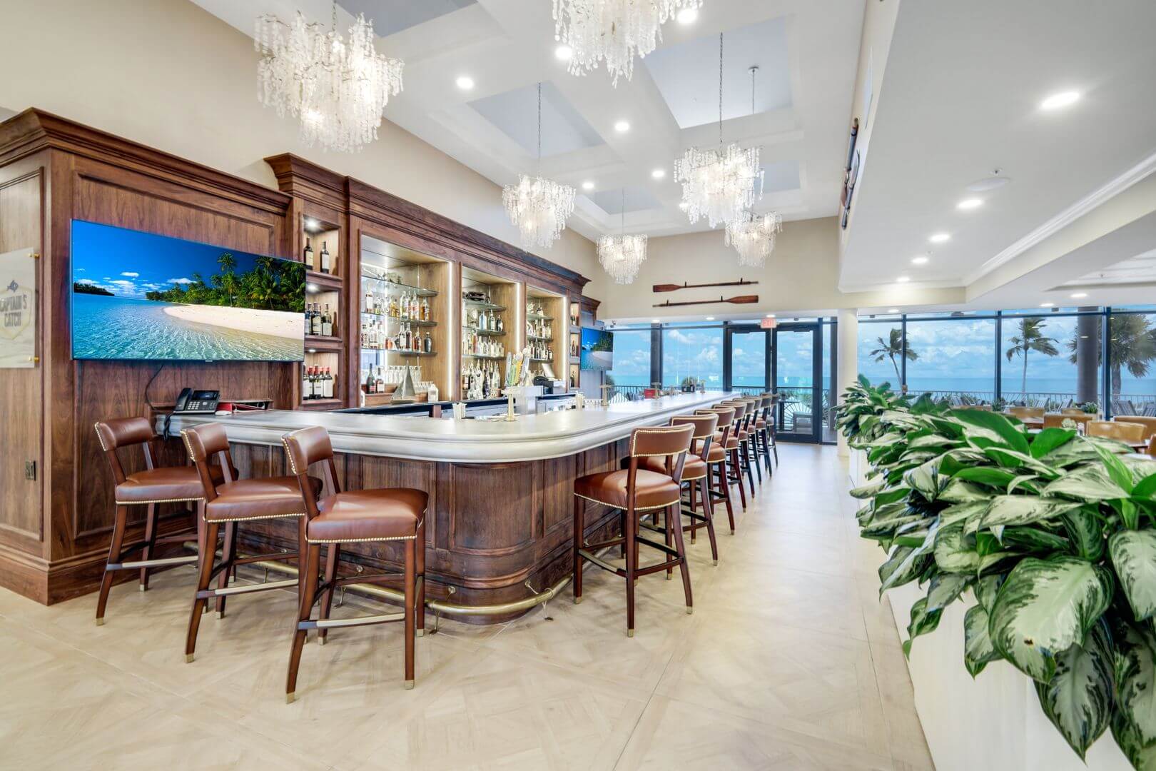 Elegant bar with ocean view and chandeliers.