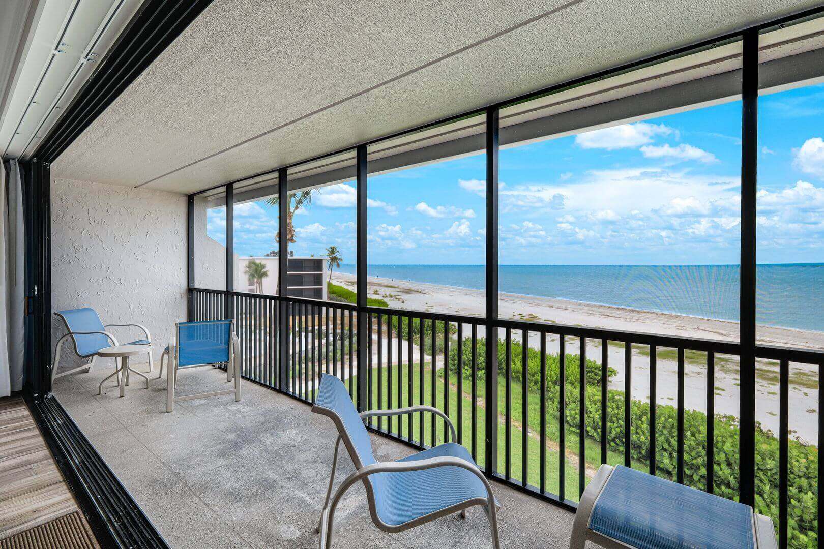 Beachfront balcony with ocean view and chairs.