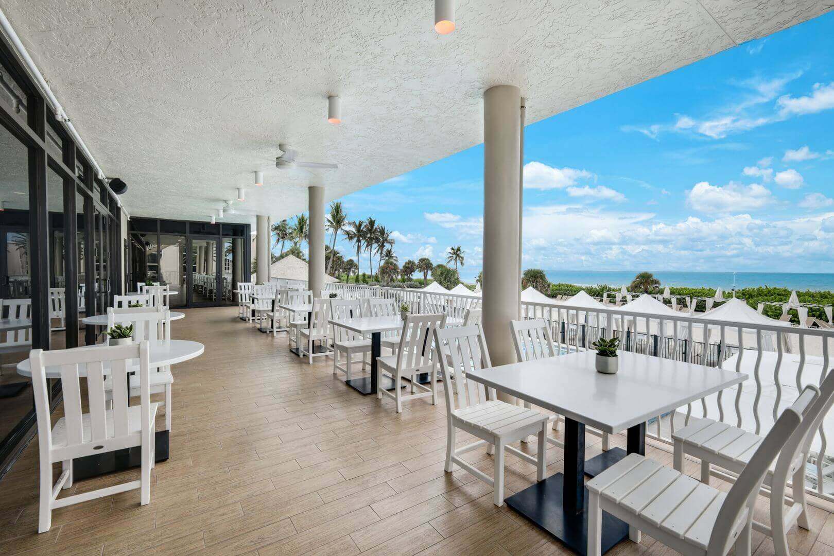 Outdoor patio with ocean view and tables.