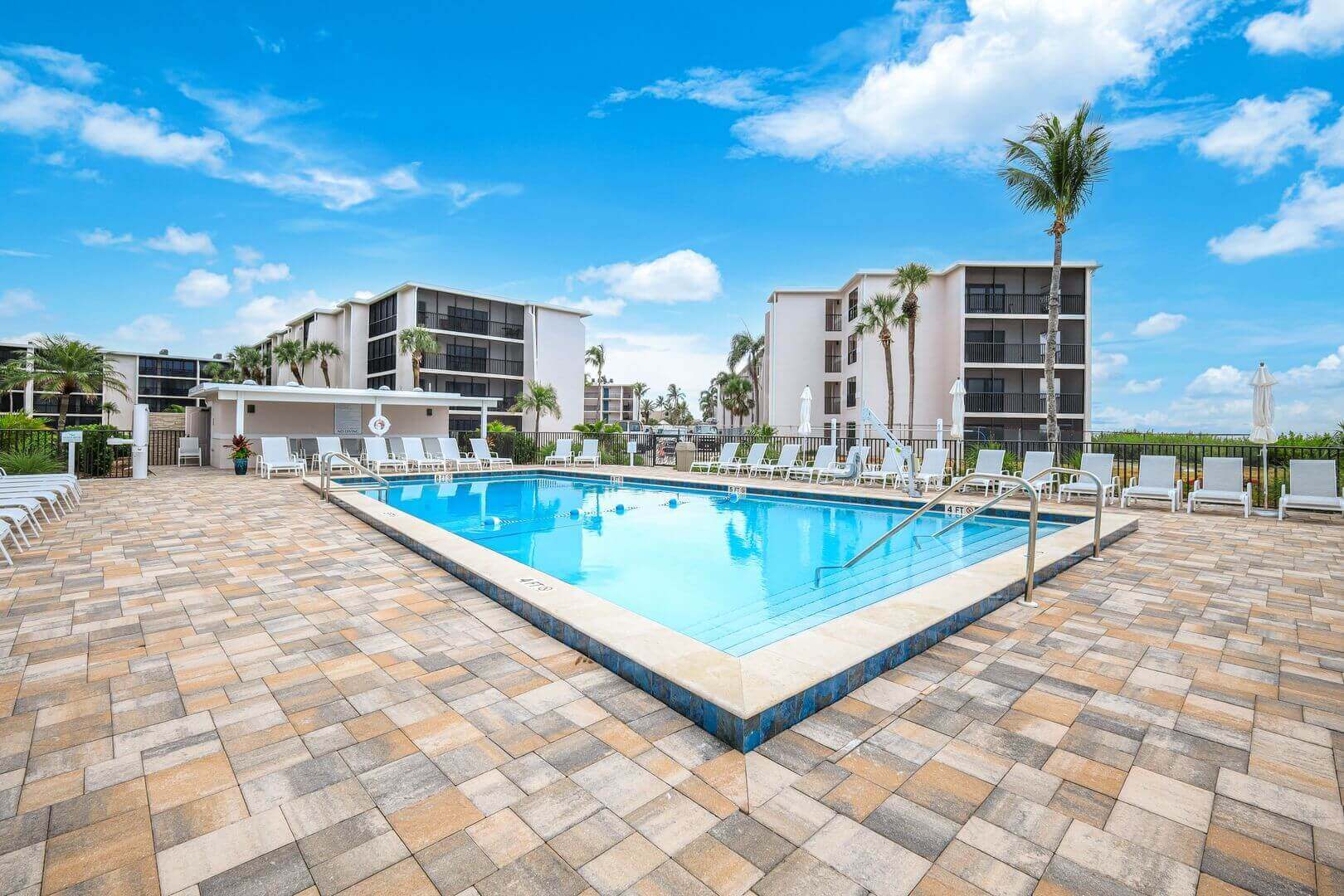 Pool area with lounge chairs and buildings.