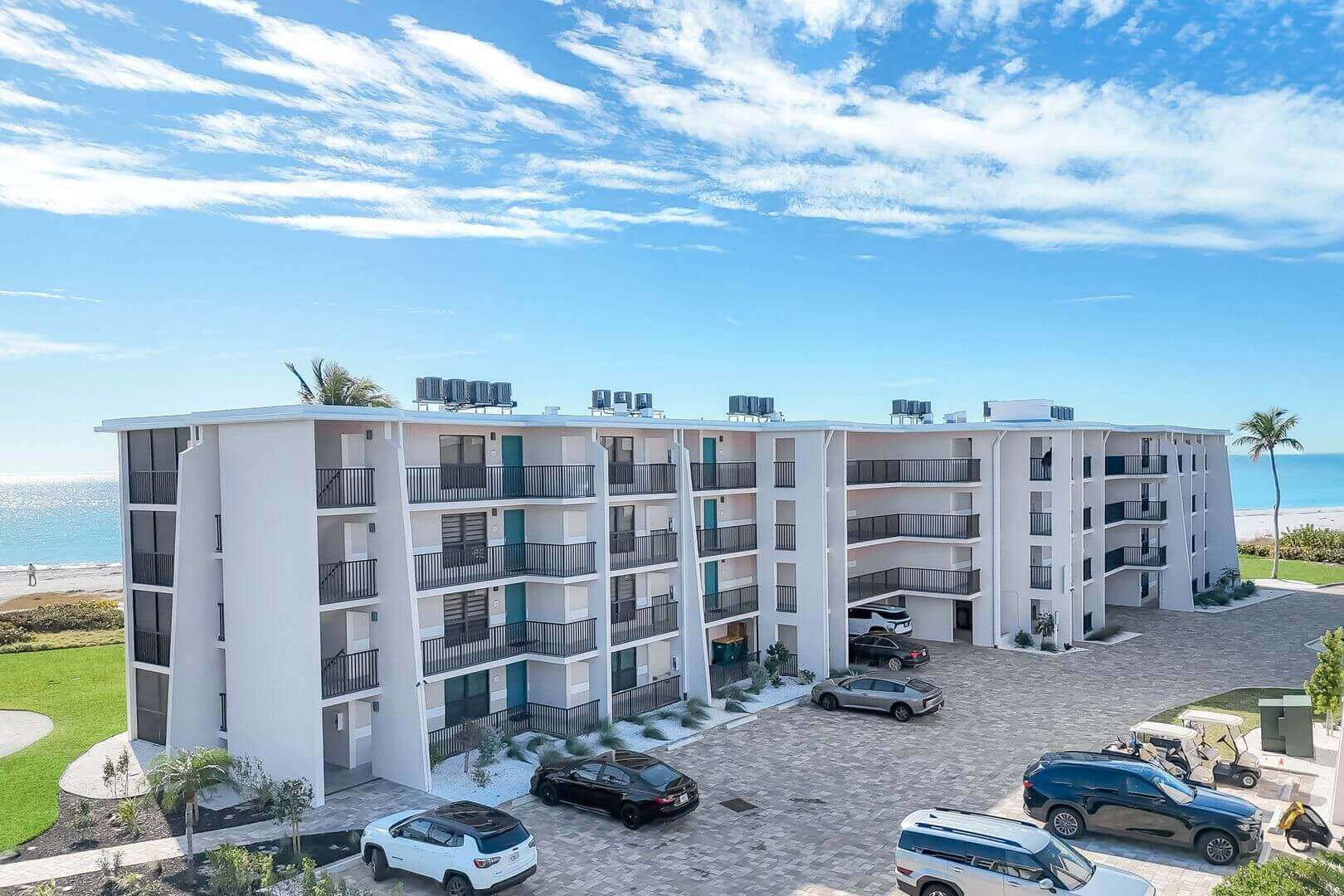 Beachfront apartment building with parked cars.