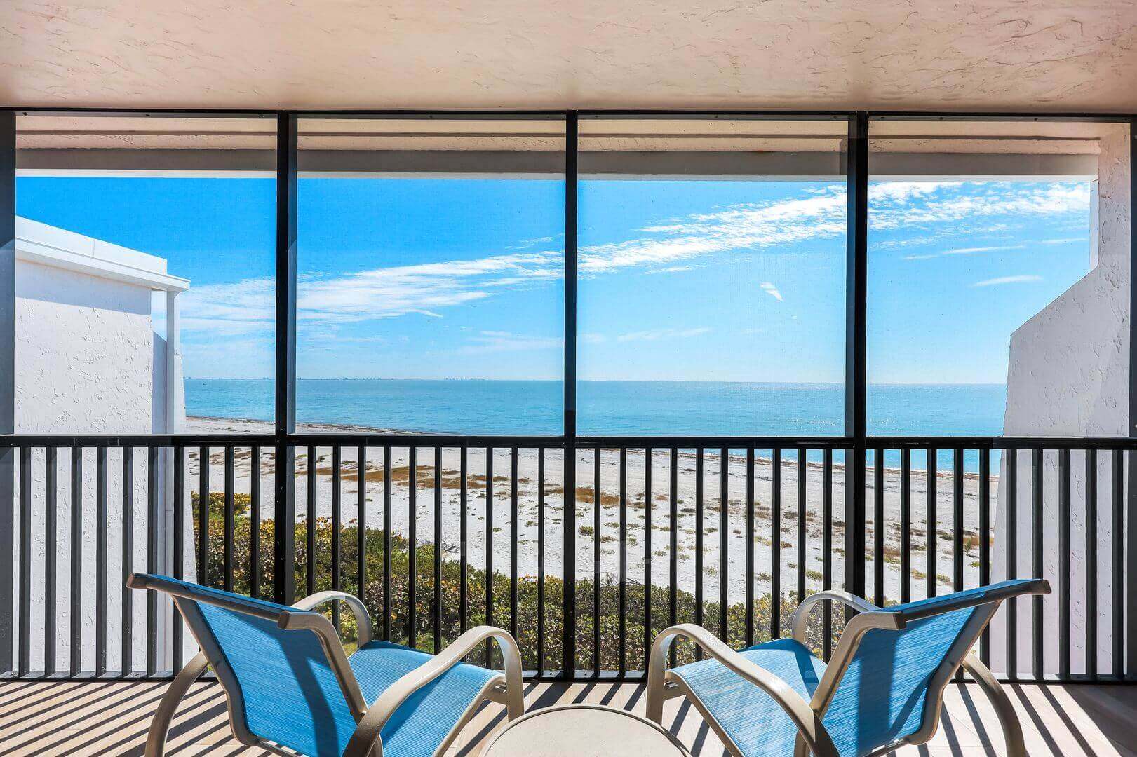 Balcony with ocean view and blue chairs.