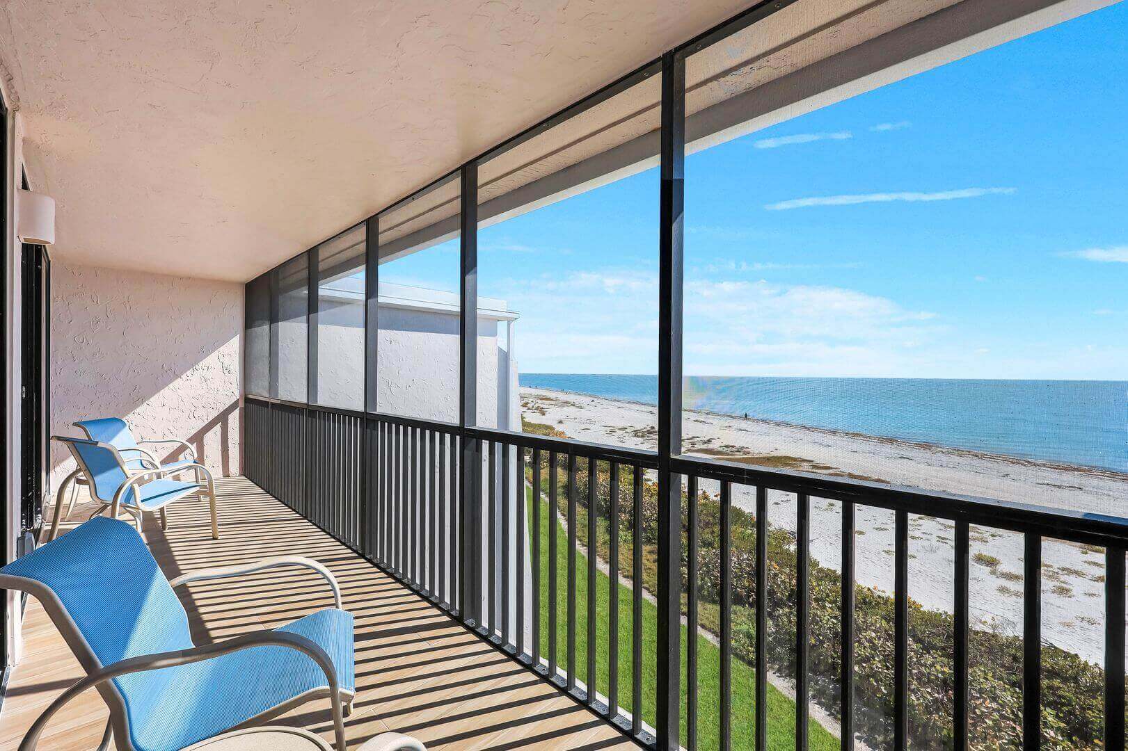Beachfront balcony with ocean view and chairs.