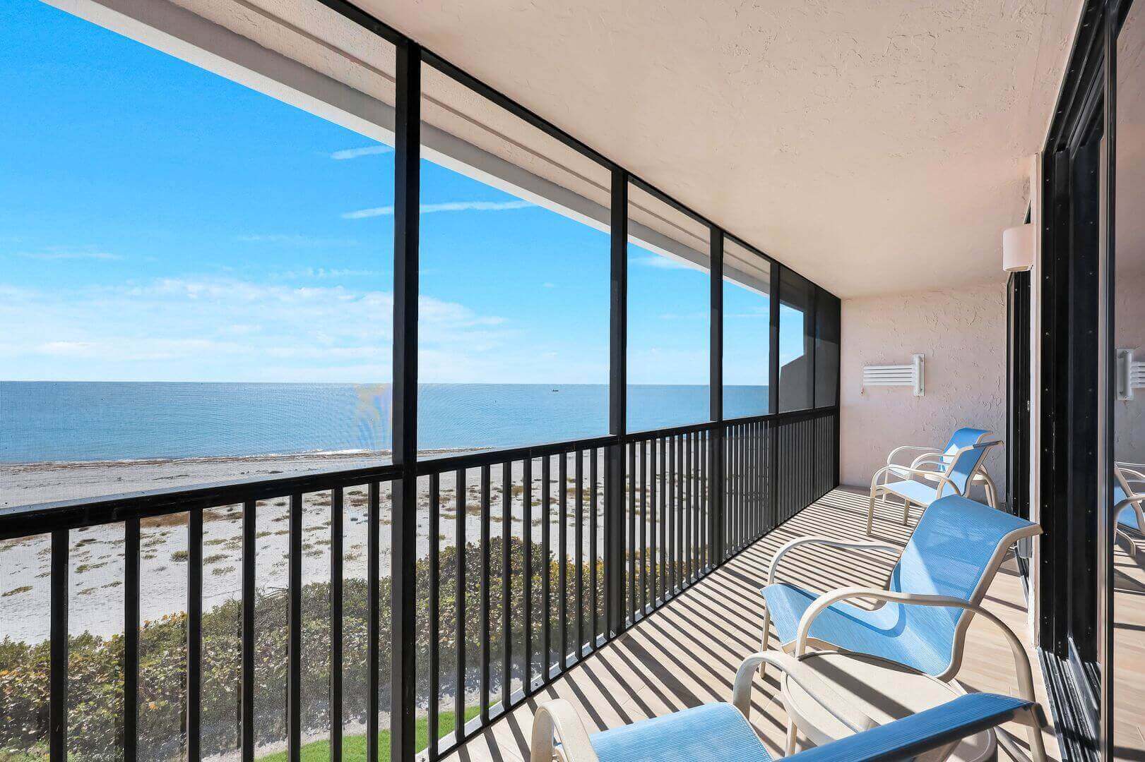 Beachfront balcony with chairs and ocean view.