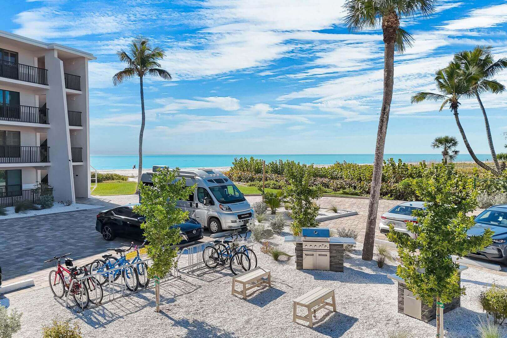 Beachfront view with parked bikes and cars.