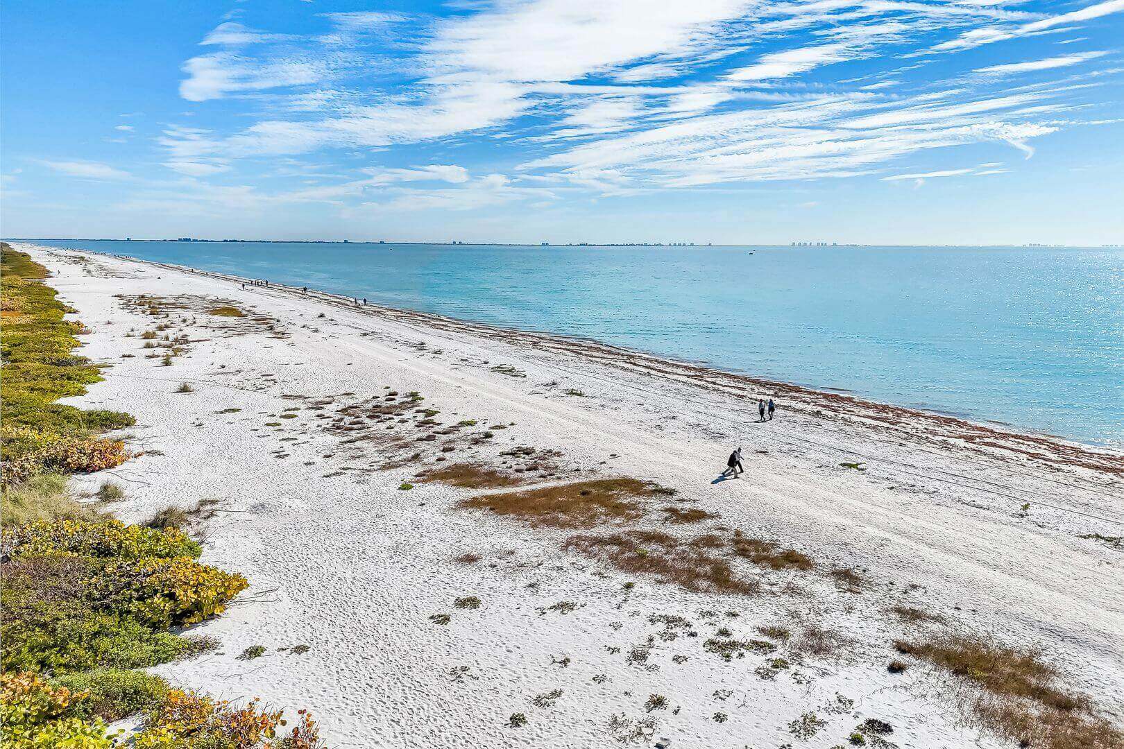 Sandy beach with ocean and blue sky.
